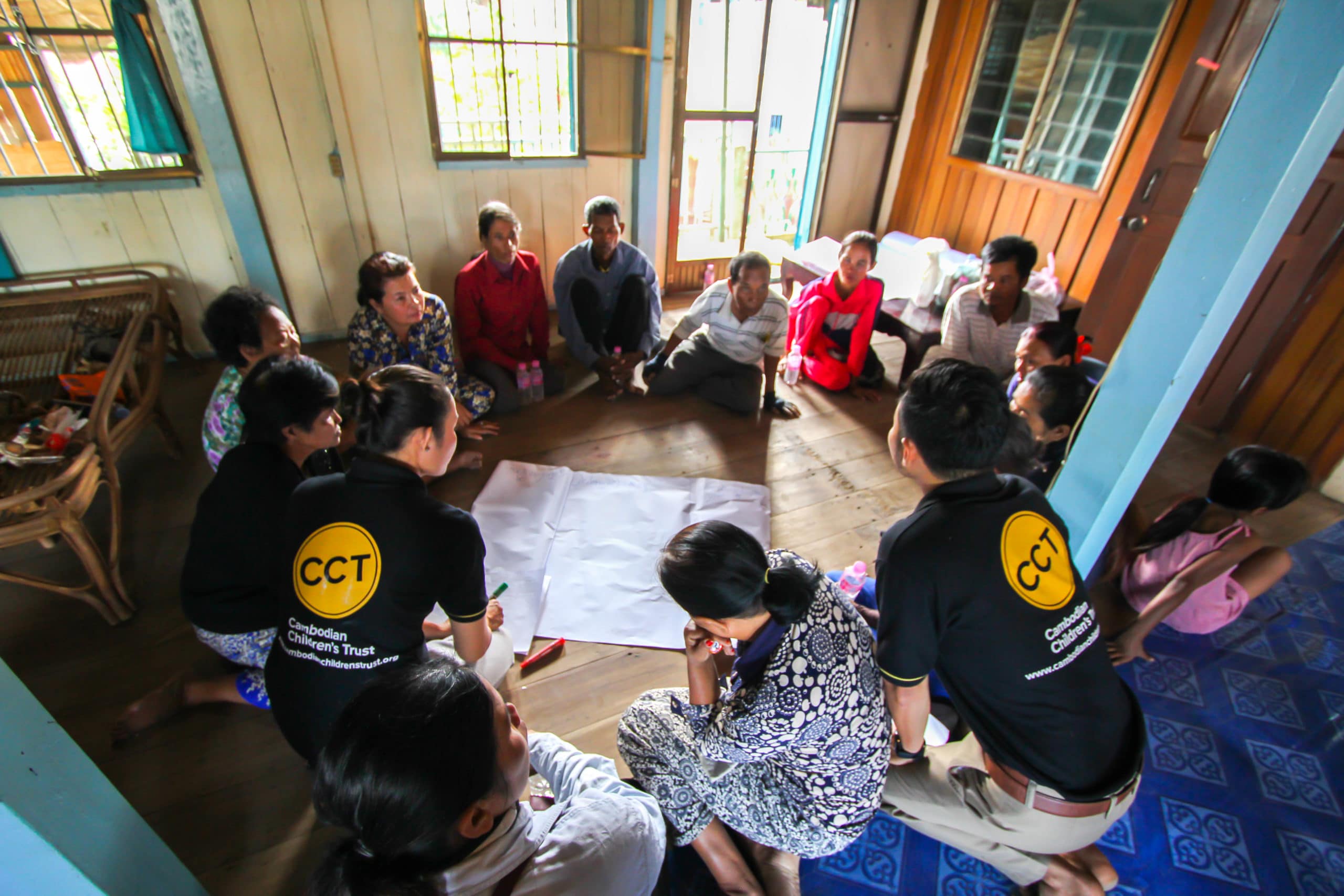 CCT team members working with community members, providing a Parenting skills workshop while seated in a circle on the floor