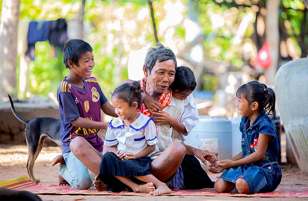 4 smiling Cambodian children with their father